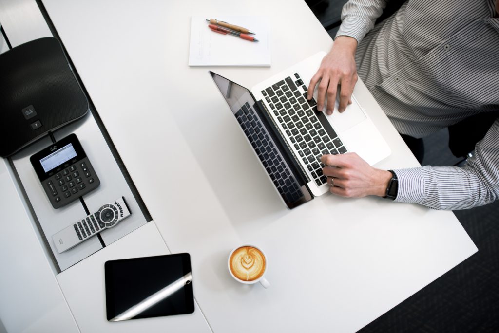 a man typing at his laptop with other work accessories around him
winning business