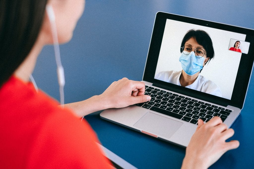 Woman with mask on screen writing an rfp during coronavirus.