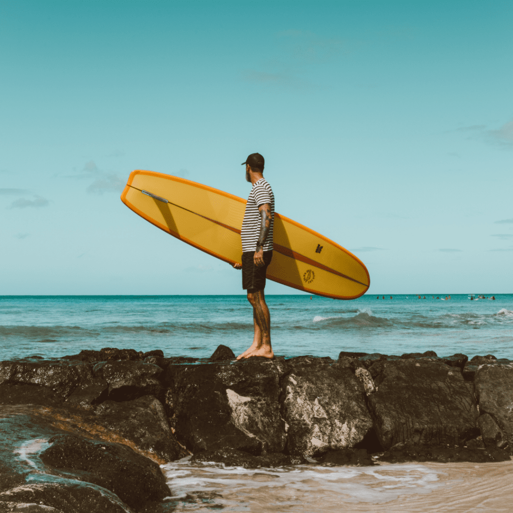 Man holding a surf board image uploaded for The Bid Lab's Featured Bid Marketing of Hawaii State Art Museum RFP.